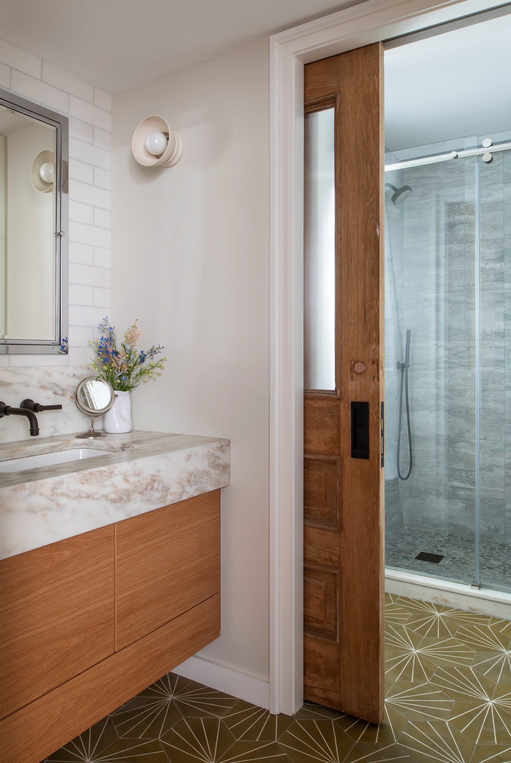 Bathroom vanity with white walls and a reclaimed wood door leading into the shower room.