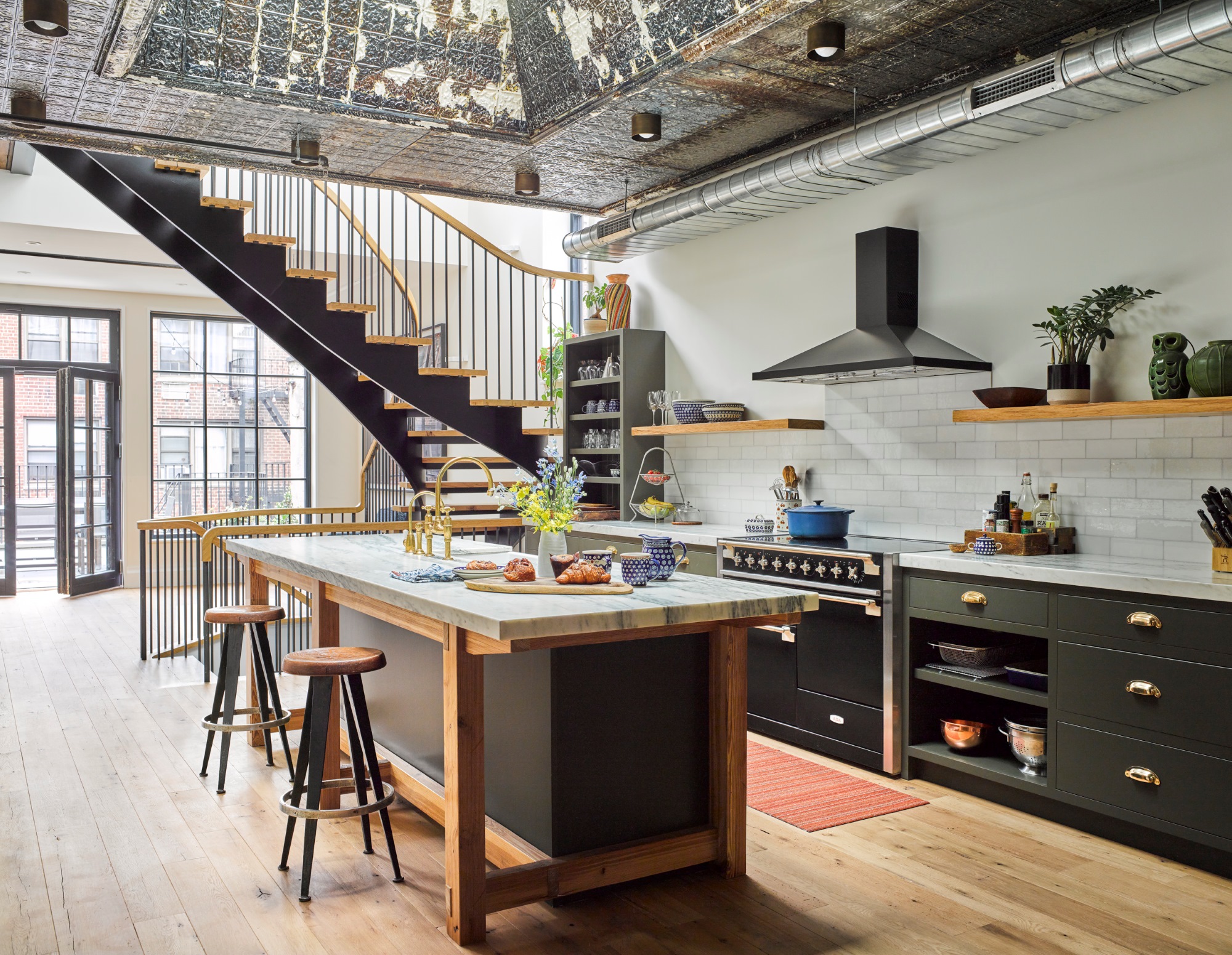 Kitchen with reclaimed tin ceilings, dark green millwork, wood floors and accents, and an open staircase leading to the lower floors of the apartment.